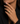 A close-up of a person's hand wearing a gold signet ring with a clear cushion-cut gemstone, styled with a black blazer.