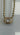 A gold ball chain necklace with an oval gold pendant setting holding a clear marquise-cut gemstone, shown against a light gray background.