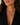 A close-up of a woman wearing a delicate gold necklace with small dark blue and white bead accents, paired with a black blazer.