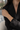 A close-up of a woman wearing a delicate, thin silver chain bracelet on her wrist, paired with a black satin blazer.
