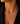 A close-up of a model wearing a delicate gold necklace with the word 'MAMA' spelled out in small letter pendants, styled with a black blazer.