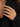A close-up of a woman's hand wearing a sparkling diamond ring with a silver-toned setting, styled on her ring finger against a black blazer.