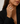 A close-up of a woman wearing a large silver-toned ring with a textured, diamond-like pattern on the finger, paired with a black blazer.