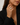 A close-up of a woman wearing a large silver-toned ring with a textured, diamond-like pattern on the finger, paired with a black blazer.