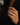 A close-up of a person's hand wearing a silver-toned emerald-cut diamond ring, set against a dark black blazer.