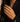 A close-up of a model's hand wearing a gold ring with a textured, diamond-like patterned face, styled with a black blazer. A decorative 'D' monogram watermark is visible in the bottom-left corner.