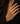 A close-up of a model's hand wearing a gold ring with a large, textured white stone, set against a black blazer.