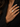 A close-up of a model's hand wearing a gold ring with a large, textured white stone, set against a black blazer.