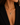 A close-up of a model wearing a delicate gold chain necklace with a heart-shaped pendant paved with small clear stones, styled with a black blazer.
